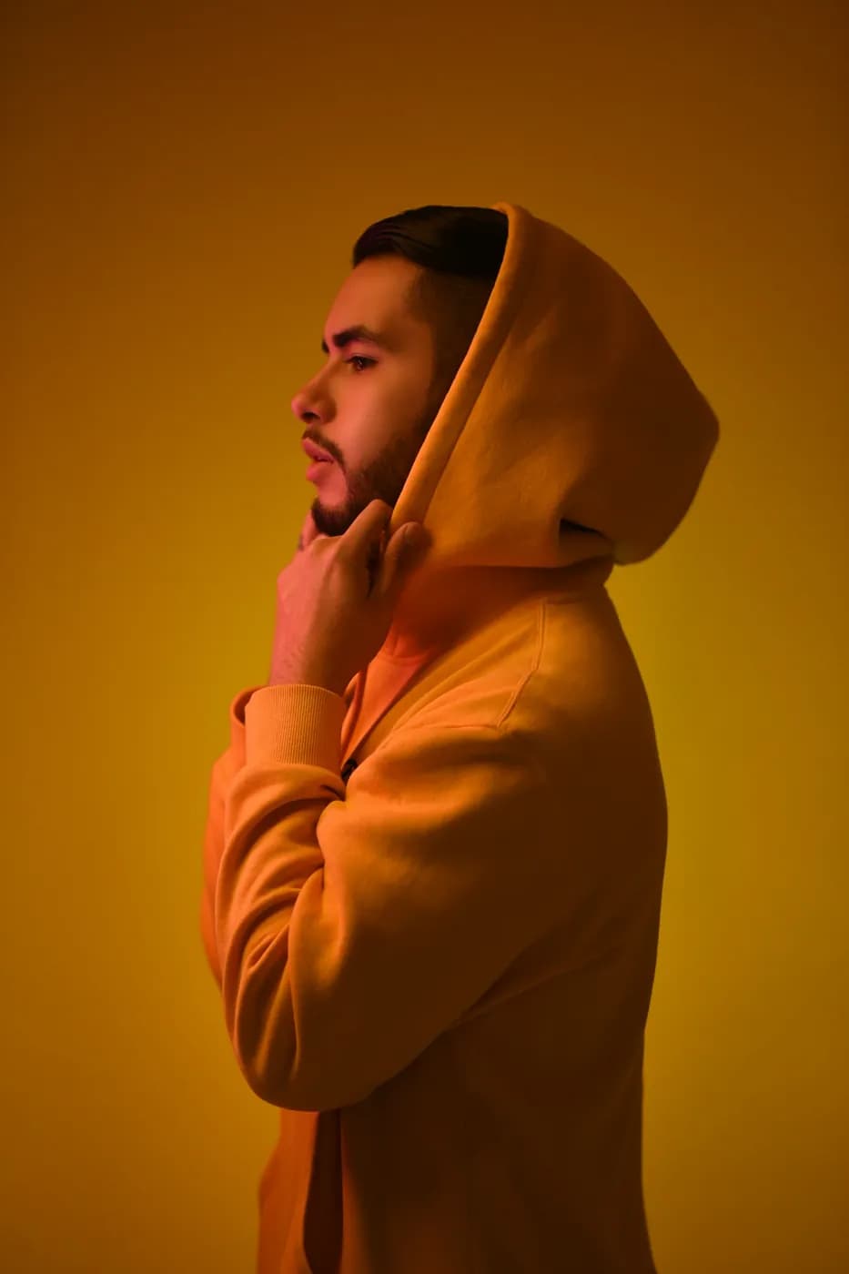 Model in a yellow hoodie against a warm yellow backdrop